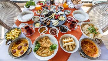 A table set with a variety of breakfast items including pastries, fruits, cheeses, and beverages.