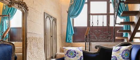 Una habitación con un sofá azul, un espejo ornamentado y una escalera.