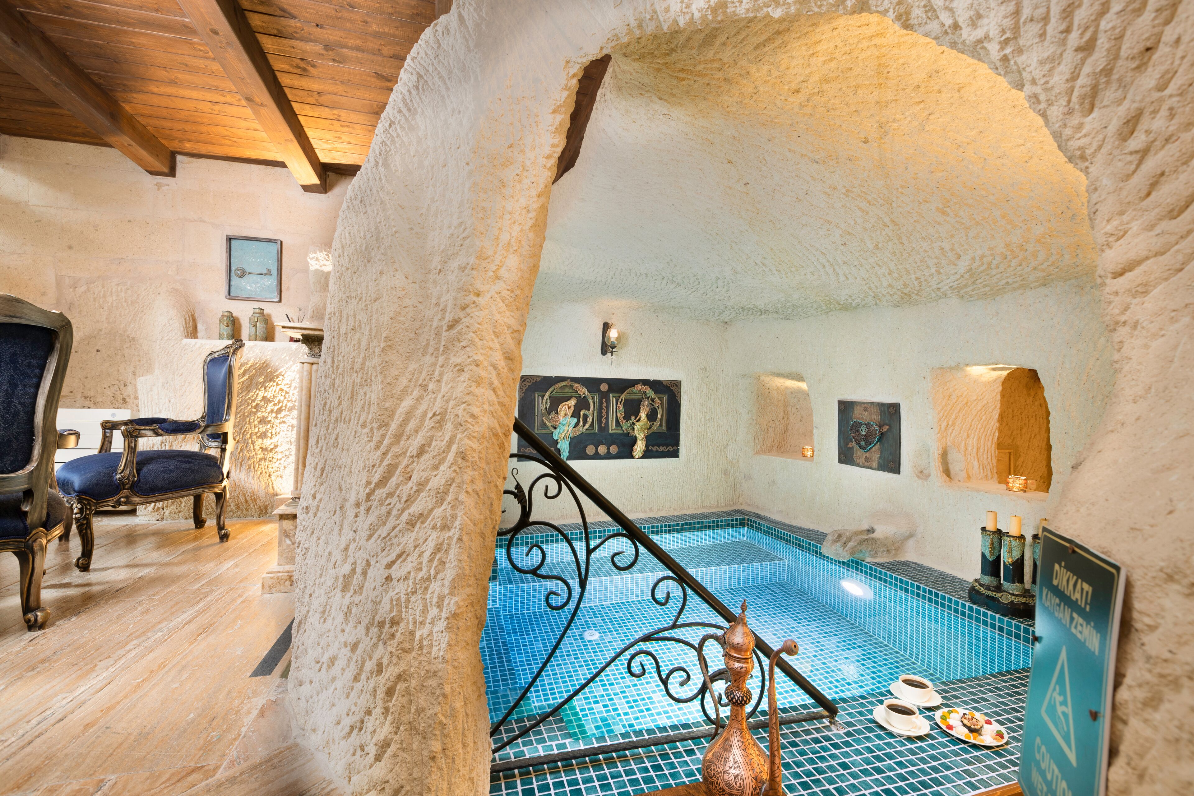 Ein Wellnessbereich mit mosaikbesetztem Pool, Holzboden und Steinwand.