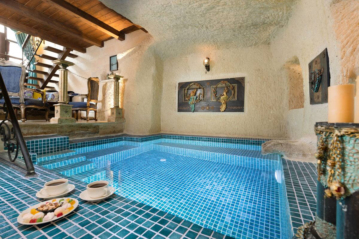 A spa pool with mosaic tiles, a staircase, and a wall-mounted artwork.