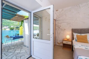 Ein Schlafzimmer mit Bett, Nachttisch und Blick auf Pool und Berge.