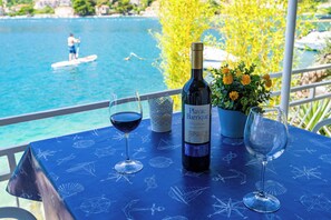 Ein Tisch mit einer Weinflasche und zwei Gläsern, vor einer malerischen Wasserausicht und einer Person, die auf einem Stand-Up-Paddleboard fährt.