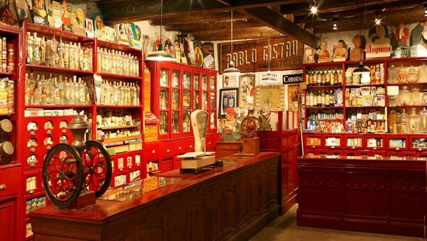 A vintage-themed bar with red shelving stocked with various bottles and canned goods. - Casa amb vistes al Pallars Jussà (Conca de dalt)