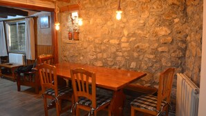 A rustic dining area with a wooden table and chairs, stone walls, and hanging light fixtures. - Casa amb vistes al Pallars Jussà (Conca de dalt)