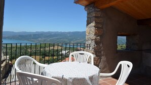 A balcony with a view of a lake and mountains, white chairs, and a table with a polka dot tablecloth. - Casa amb vistes al Pallars Jussà (Conca de dalt)