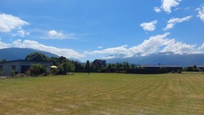 Um bairro residencial com um gramado, uma casa e montanhas ao fundo.