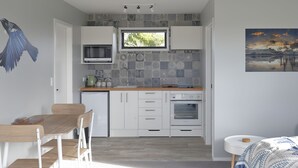 Cozinha moderna com armários brancos, micro-ondas, pia e janela com vista para o verde.