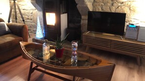 Una sala de estar acogedora con una pared de piedra, una chimenea, un televisor y una mesa de centro de madera con adornos.
