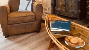 Un salón acogedor con chimenea de piedra, un sillón de cuero marrón, una lámpara y una bandeja con pasteles.