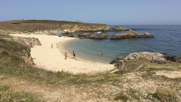 Una playa con afloramientos rocosos y agua azul cristalina.