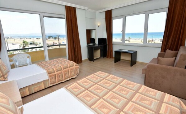 A hotel room with a balcony, a bed, a sofa, a desk, and a TV.