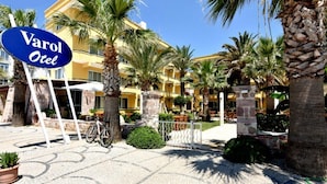 A hotel named Varol Otel with a paved courtyard, palm trees, and outdoor seating areas. - Varol Otel (Ayvalik)