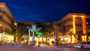 A hotel with multiple floors, outdoor seating, and palm trees. - Varol Otel (Ayvalik)
