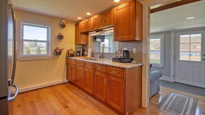 A kitchen with wooden cabinets, a stainless steel refrigerator, and a window.