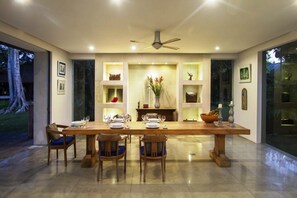 A dining area with a long wooden table, four chairs, and a ceiling fan. - Villa Alam Taru (Cemagi)