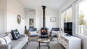A cozy living room with a fireplace, comfortable seating, and a television. - Ohana - Amazing Views (Gerroa)
