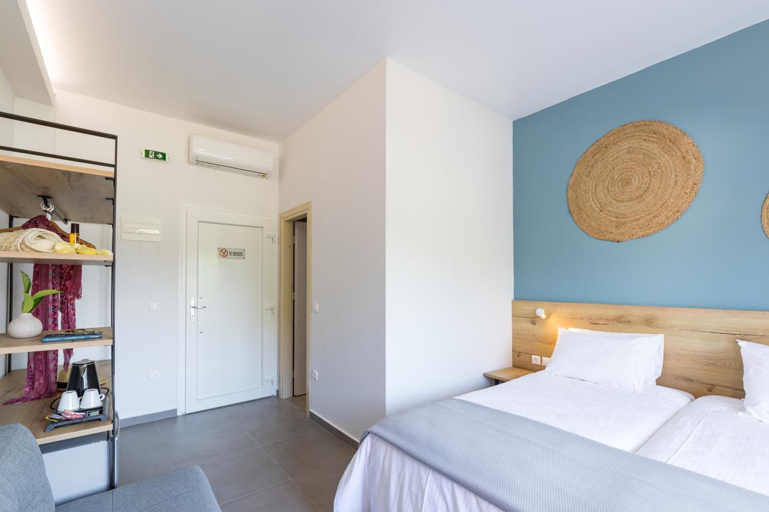 Hotelkamer met een bed, een bureau met stoel, een kledingkast en een wandplank.