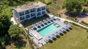 An aerial view of a modern hotel with a rooftop pool, multiple balconies, and a well-maintained garden area. - La Maison Corfu - Adults Only (Corfu)