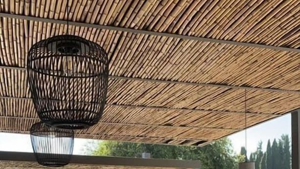 An outdoor dining area with bamboo ceiling, stone walls, and a view of greenery. - La Maison Corfu - Adults Only (Corfu)