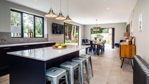 A modern kitchen with a large island, bar stools, and pendant lighting. - Broad House  - sleeps 8 guests  in 4 bedrooms (Dilham)