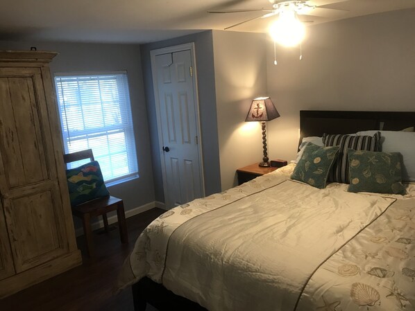 A bedroom with a bed, a nightstand, a lamp, a chair, and a wardrobe.
