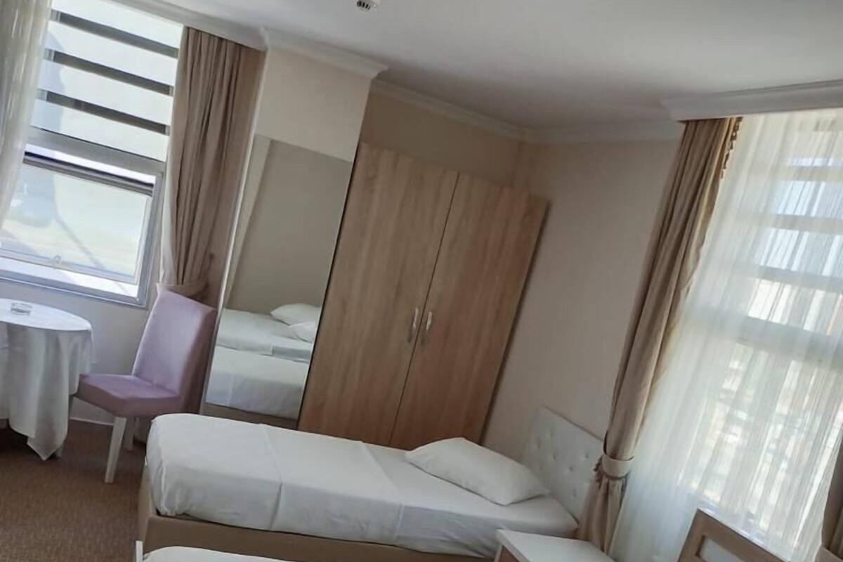 Habitación de hotel con dos camas, una mesita, una silla y un armario.
