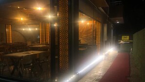 A restaurant with a red carpet entrance, tables, and chairs visible through the glass. - Otel Bostanci (Izmit)