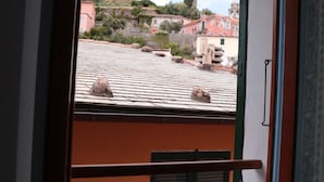 A window with a view of a building's roof and a stone structure.