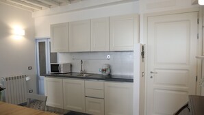A compact kitchen with white cabinets, a microwave, a sink, and a patterned floor.
