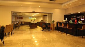 A hotel lobby with a bar area, seating arrangements, and a large mirror reflecting the space. - Betel Beach Flat (Recife)