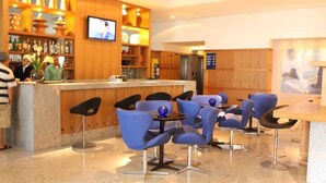 A hotel lobby with a bar area, seating, and a television screen. - Betel Beach Flat (Recife)