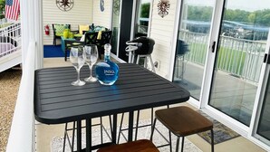Un patio cubierto con una mesa dispuesta para dos personas, que incluye una botella de JINSQ Sauvignon Blanc y dos copas de vino.