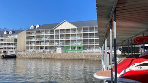 Un hotel de varios pisos con balcones, un muro de piedra y un muelle con barcos.
