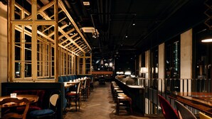 En restaurant med en lang disk, træstole og borde.