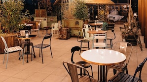Un espace extérieur aménagé en terrasse, avec des guirlandes lumineuses, des tables et des chaises.