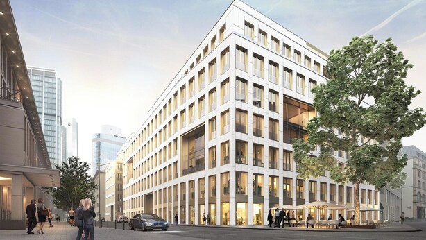 Un bâtiment moderne avec une façade composée d’une grille de fenêtres, un toit plat et un arbre devant.