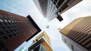A view of tall buildings with a plane flying between them. - Ruby Louise Hotel Frankfurt by IHG (Frankfurt)