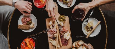 A round table with various food items and drinks, surrounded by people.