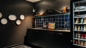 A modern kitchen with dark cabinetry, a blue-tiled backsplash, and a coffee machine.