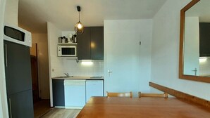 Eine kompakte Küche mit Mikrowelle, Herd und Spüle. Ein Holzespeisetisch mit Stühlen steht bereit.