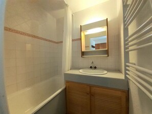 A bathroom with a bathtub, a sink, and a mirror.