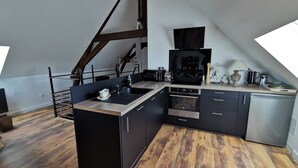 Ett modernt kök med en central köksö, en inbyggd ugn och ett trägolv.