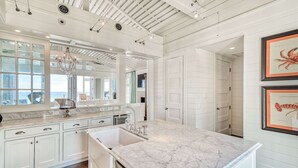 A spacious kitchen with white cabinetry, a marble countertop, and a view of the ocean through large windows. - Gulf Front in the Middle of Seaside! Elevator, Community Pools, Bikes, and More (Santa Rosa Beach)