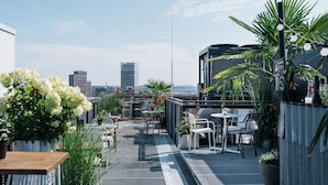 Terraza en la azotea con mobiliario exterior, plantas en macetas y vistas del horizonte de la ciudad.
