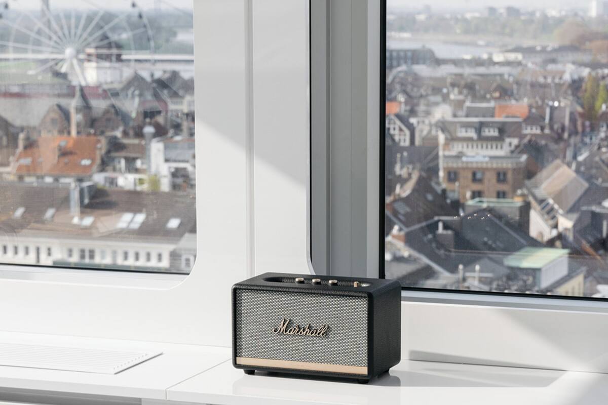 A Marshall speaker on a windowsill with a view of a cityscape and a Ferris wheel.