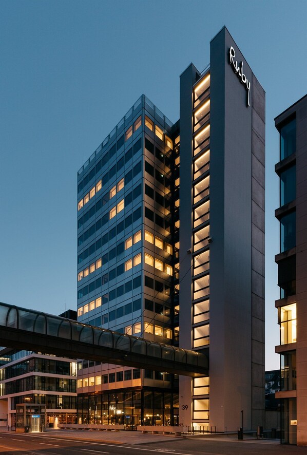 Un hotel moderno con un llamativo letrero 'Ruby', fachada de vidrio y una cubierta walkway.