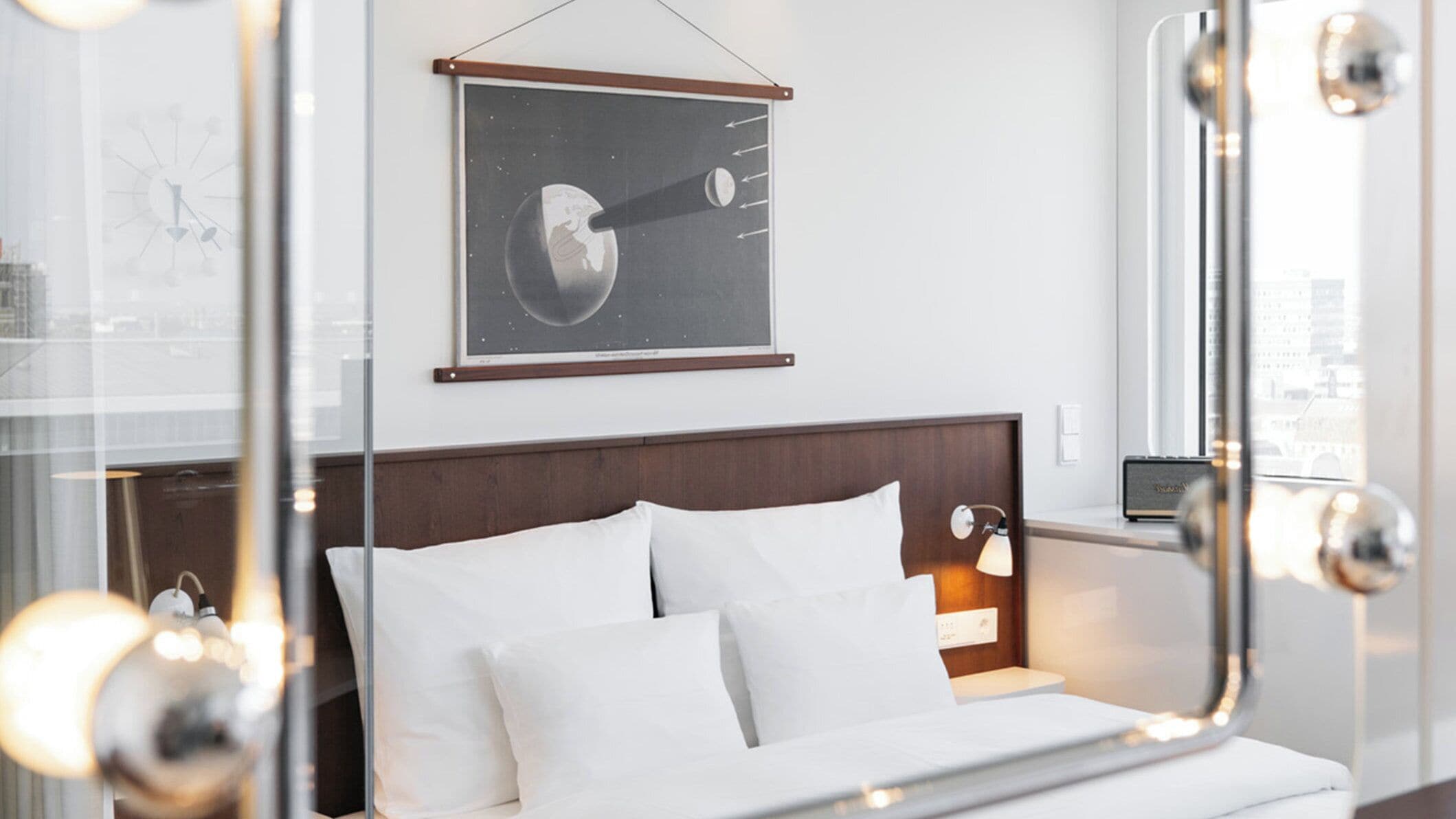 Ein Hotelzimmer mit Bett, Nachttisch, einem gerahmten Bild an der Wand und einem Fenster mit Blick.