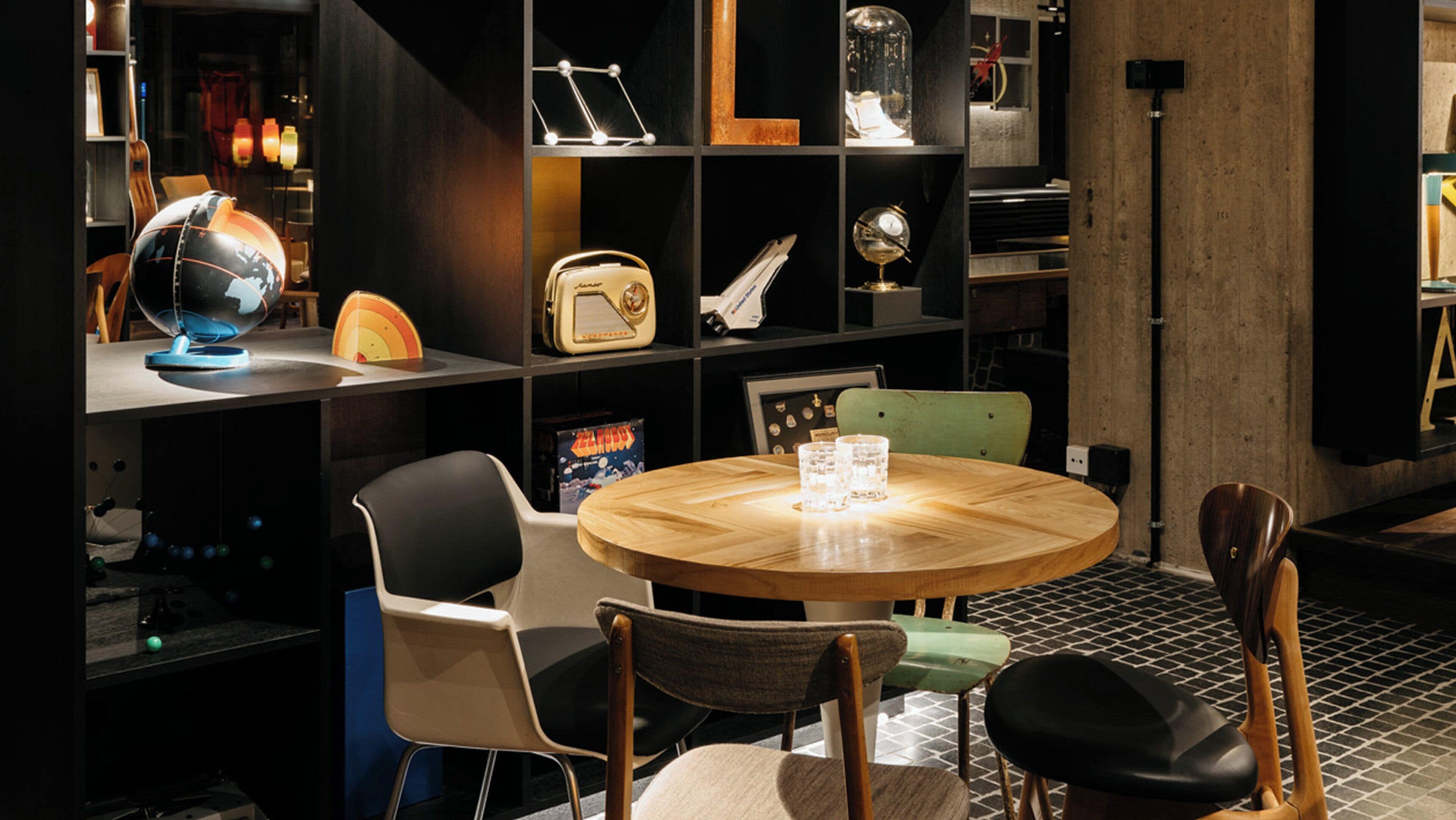 A round wooden table with chairs, a globe, a vintage radio, and a telescope.