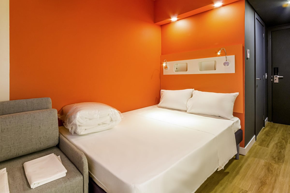 Een hotelkamer met een bed, een slaapbank en een kledingkast.