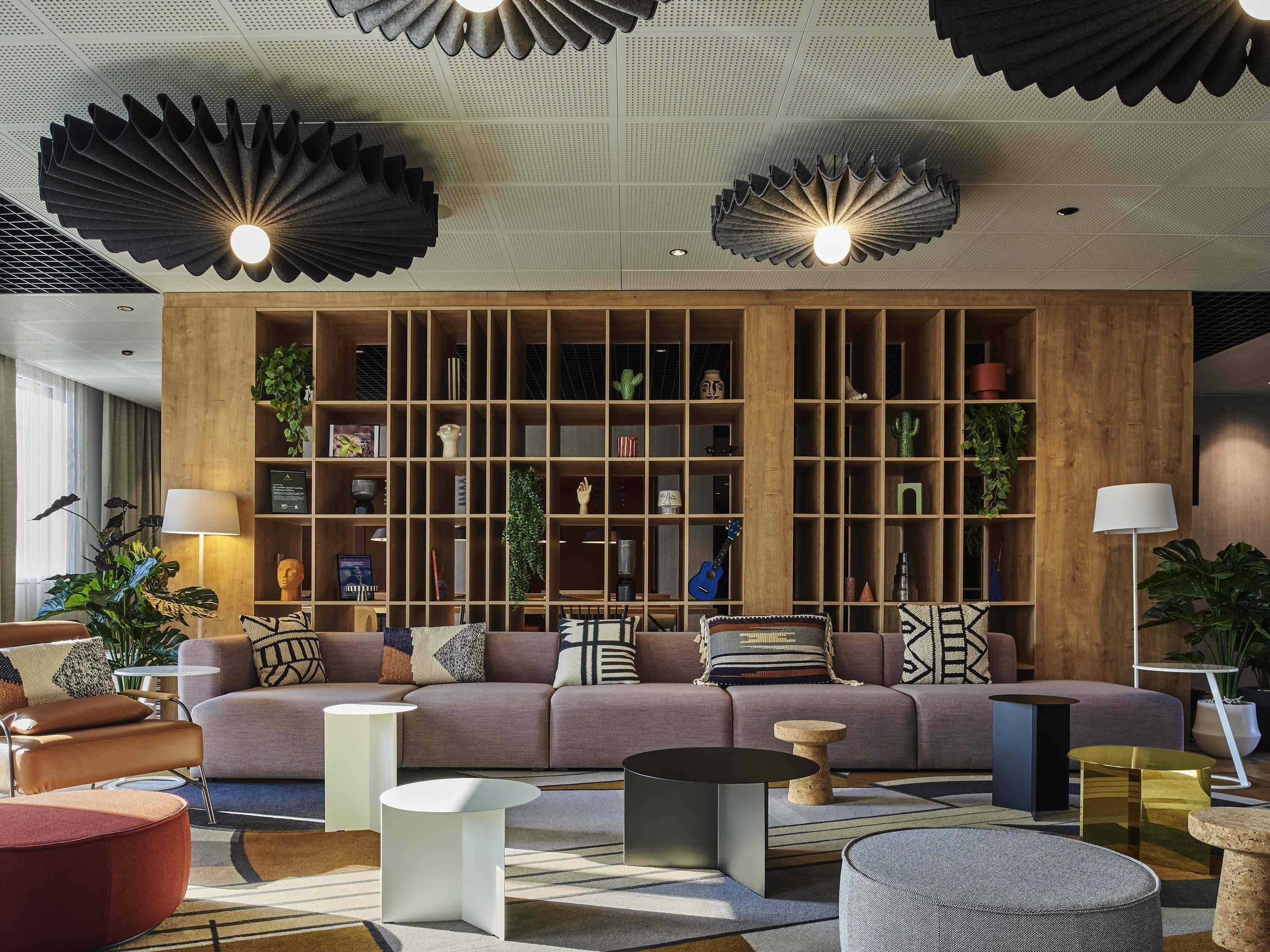A modern living room with a sectional sofa, round coffee tables, and a wooden bookshelf.